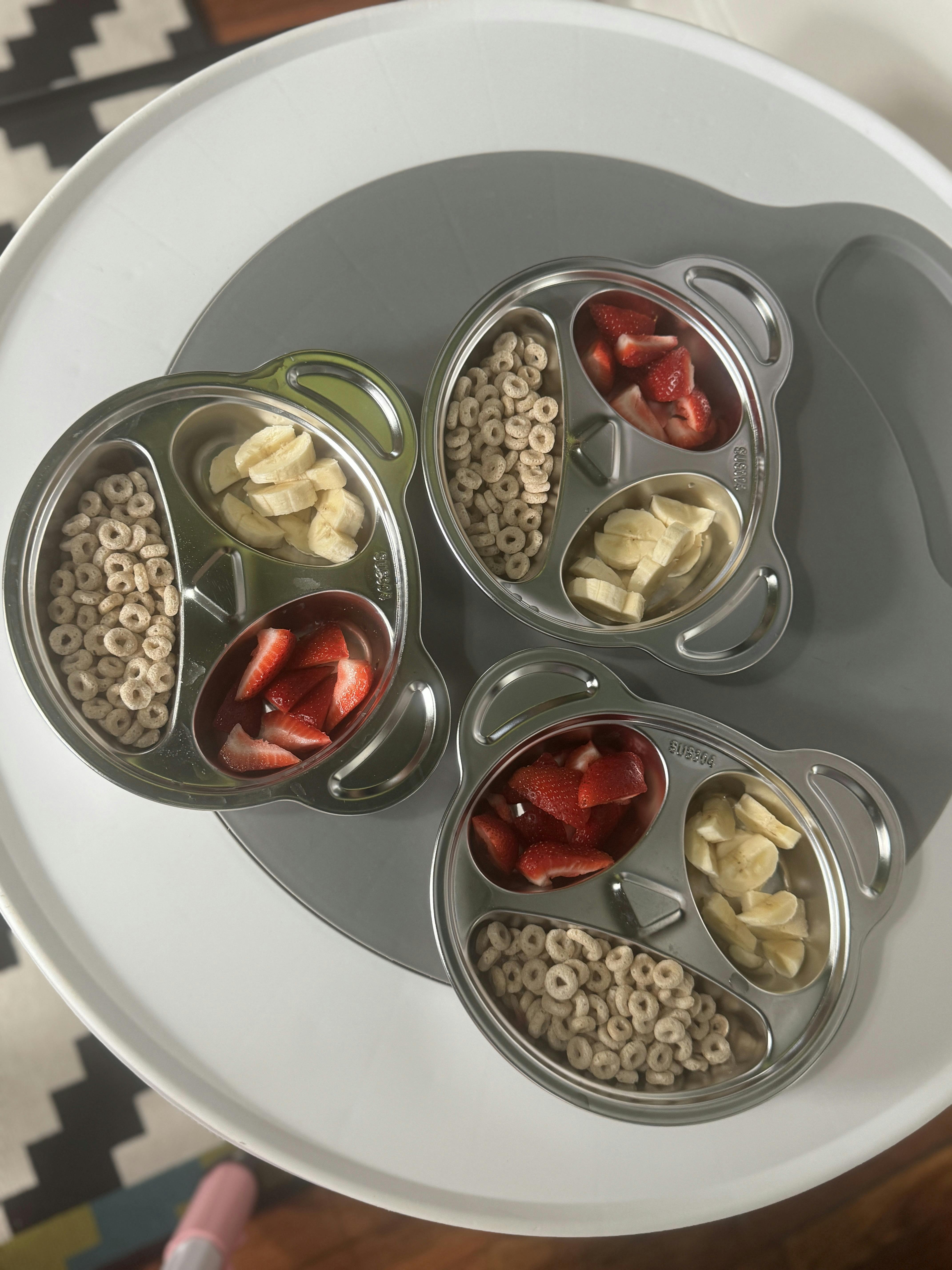 Three bear-shaped metal plates with cereal, strawberries, and sliced bananas