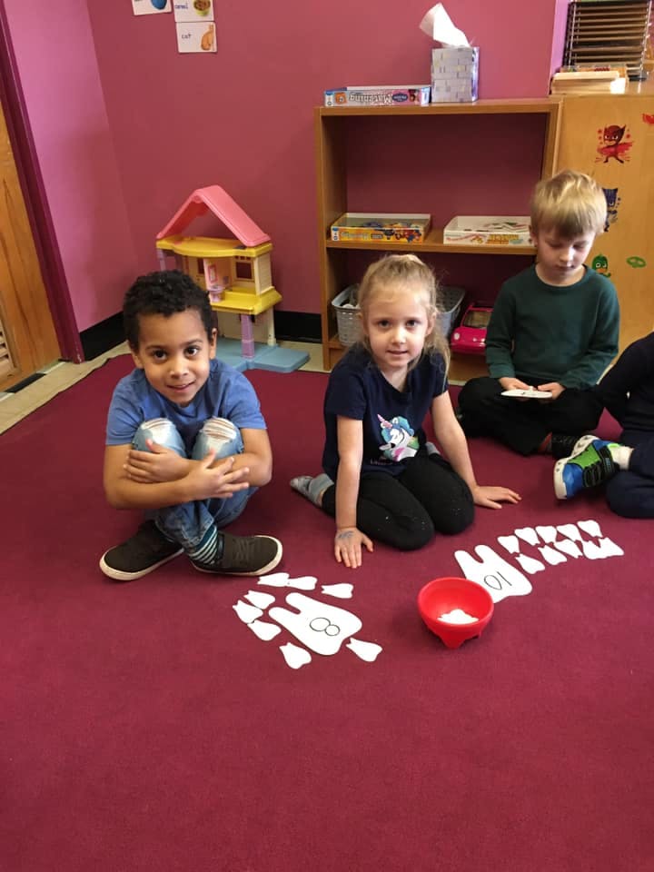 Three children sitting on a red carpet with tooth-shaped cutouts
