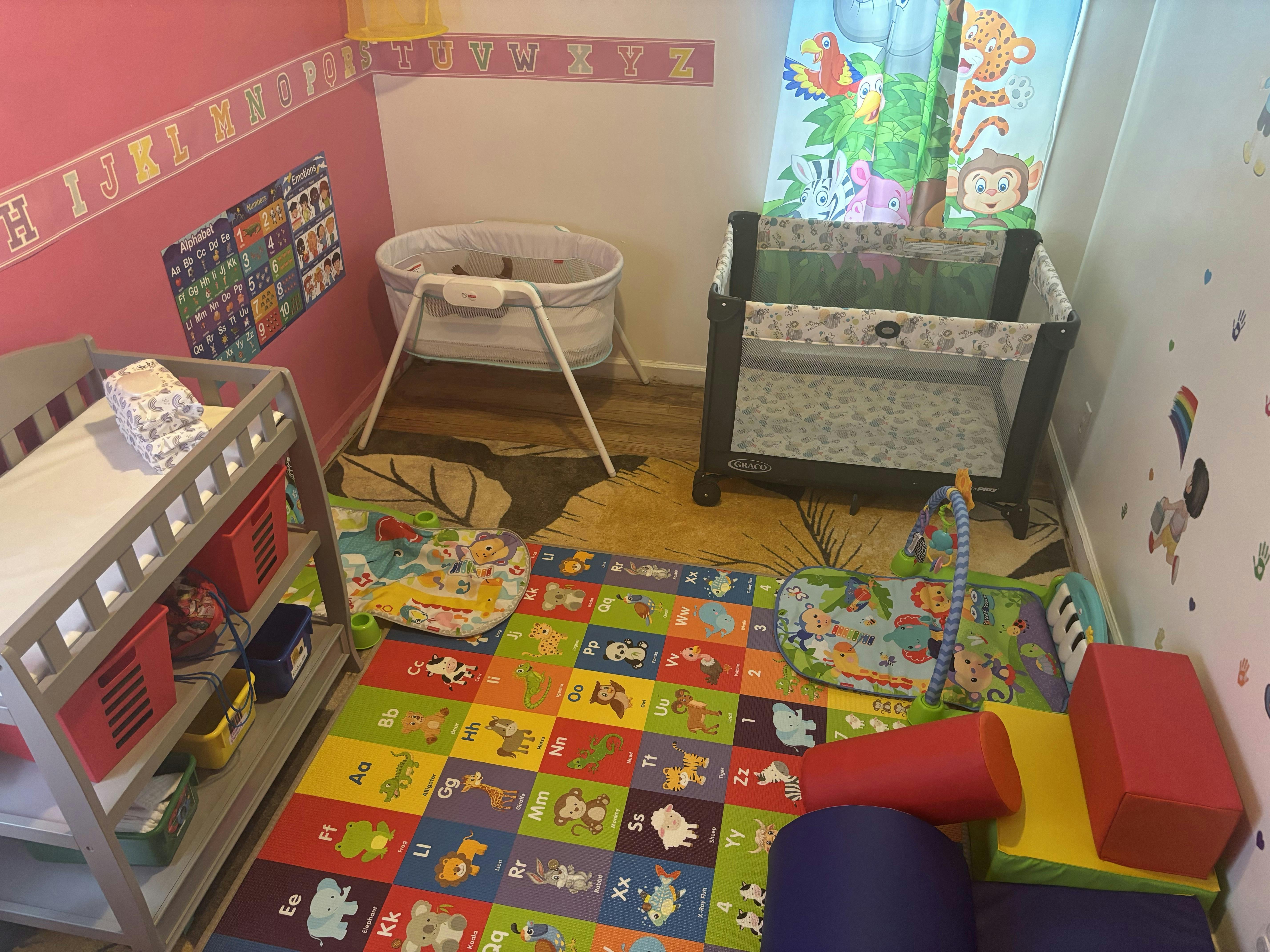 Nursery room with crib, bassinet, changing table, and colorful playmat