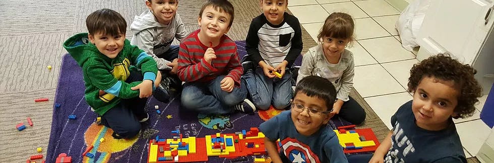 Group of children sitting on a rug with building blocks