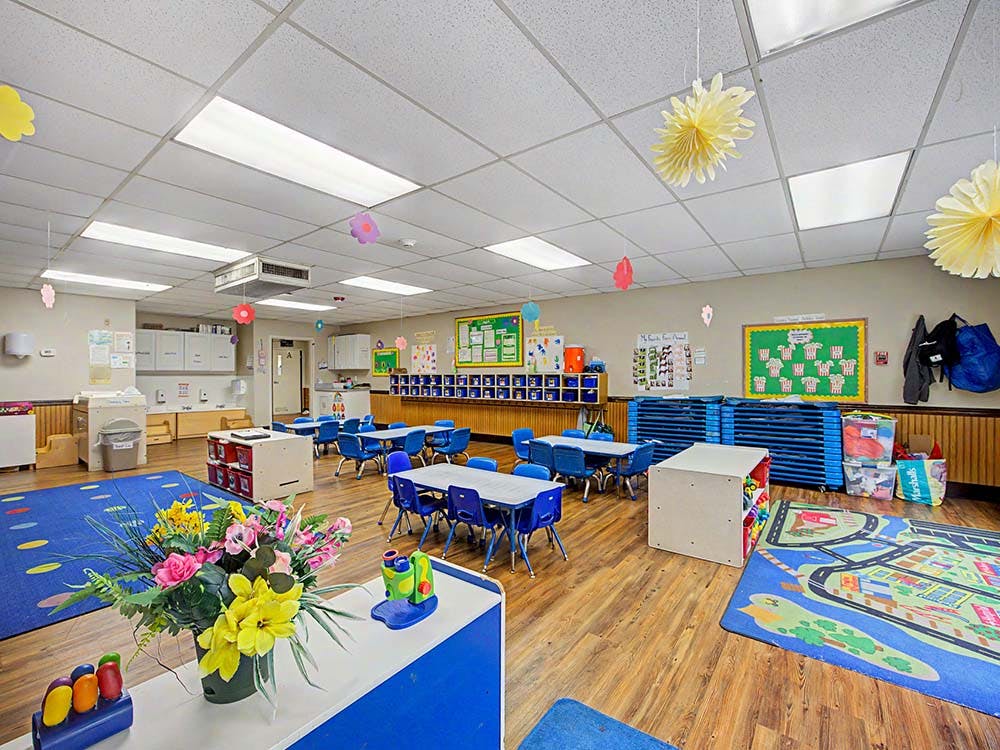 Empty colorful children's classroom with small tables, chairs, and play mats