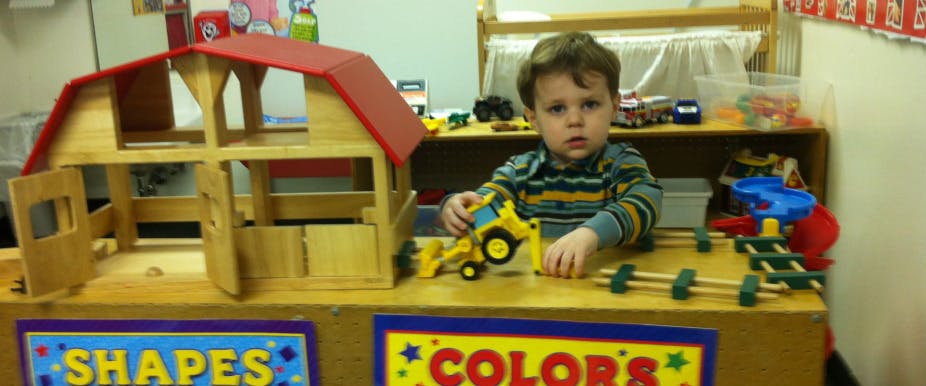 Child playing with a toy tractor and barn