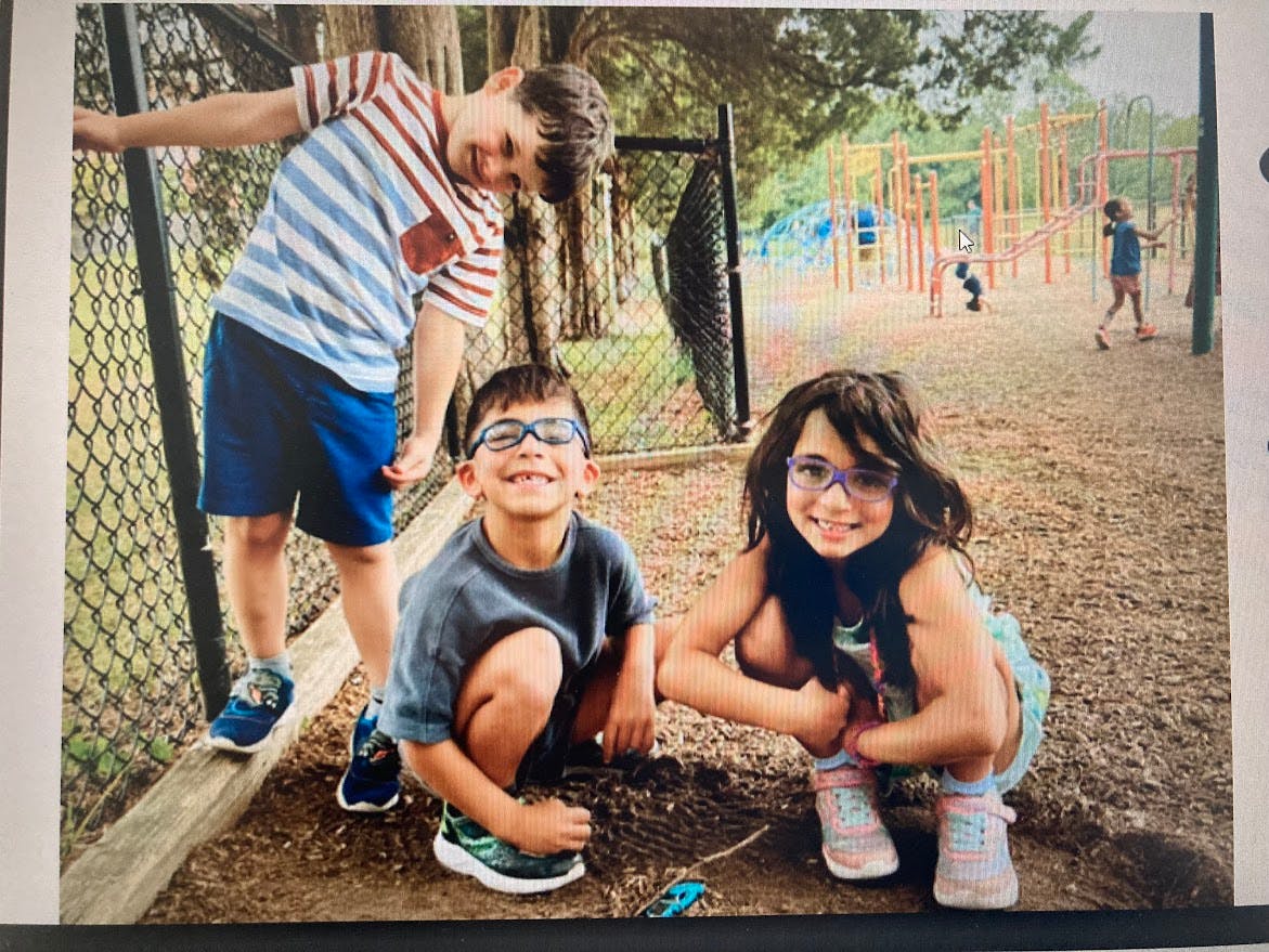 Three children posing for a photo at a playground
