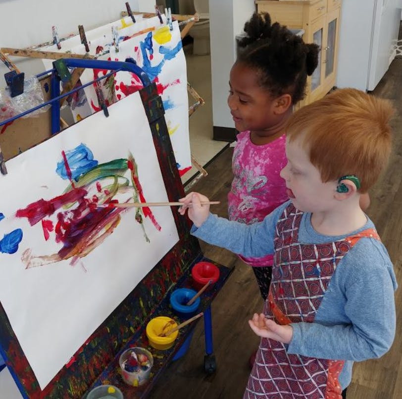 Two children painting at an easel