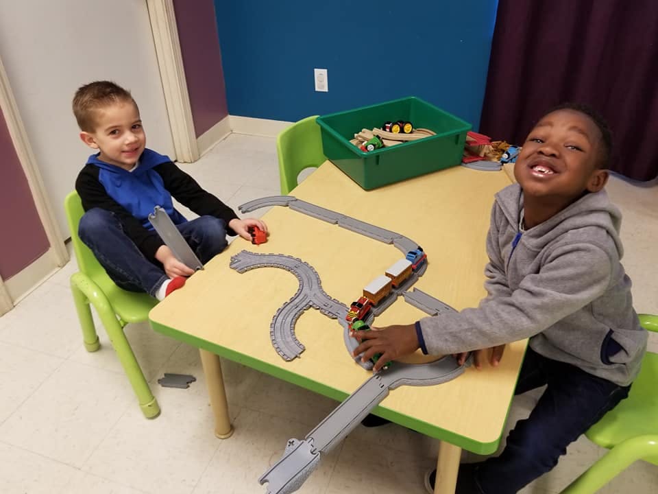 Two children playing with a toy train set on a table
