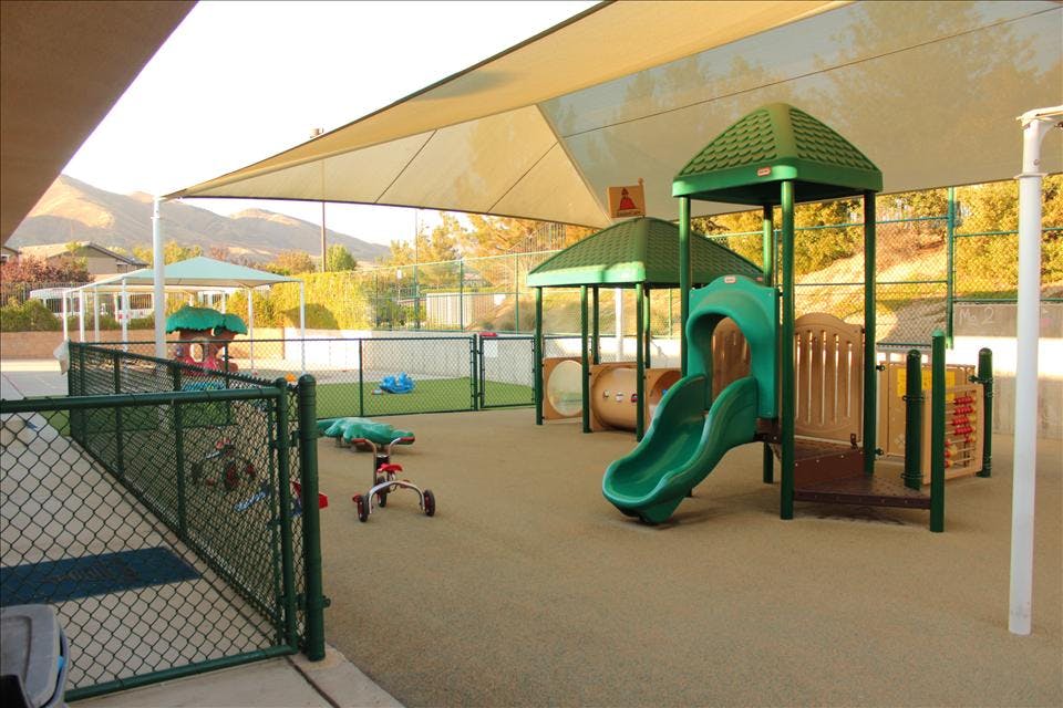 Playground area with shade canopy, green slides, and other play structures