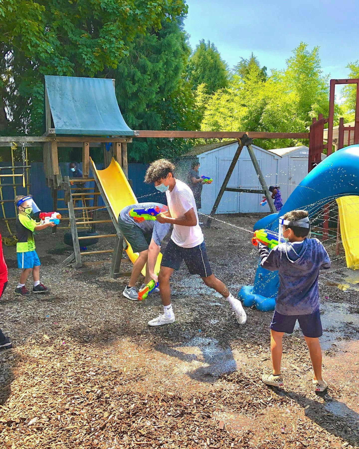 Teens and children playing with water guns outdoors