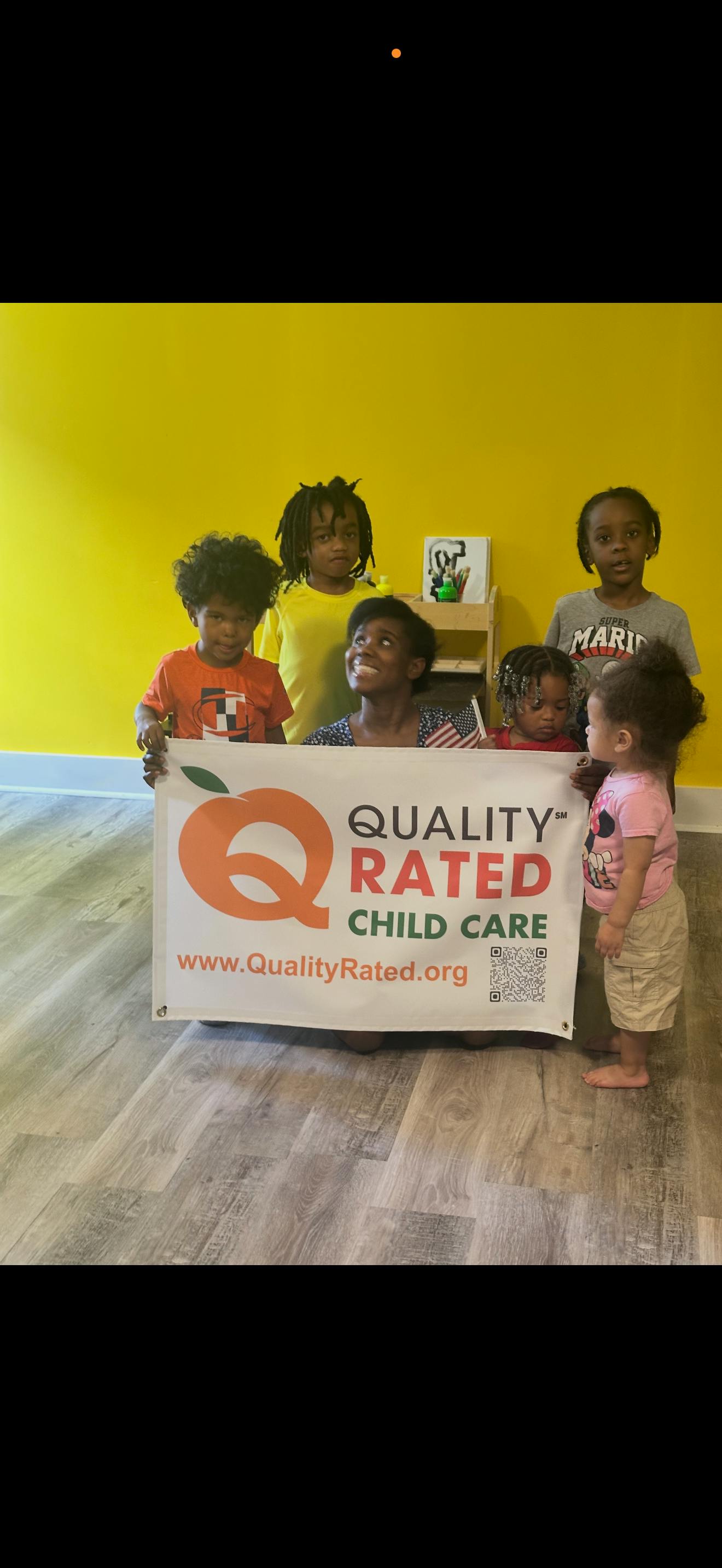 A person and five children holding a Quality Rated Child Care banner