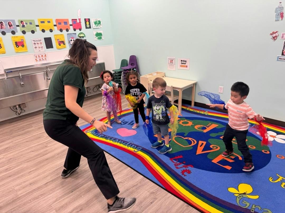 Teacher and children playing with colorful scarves on a classroom rug