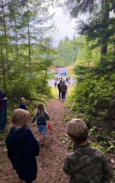 People walking along a dirt trail in a forest toward a clearing