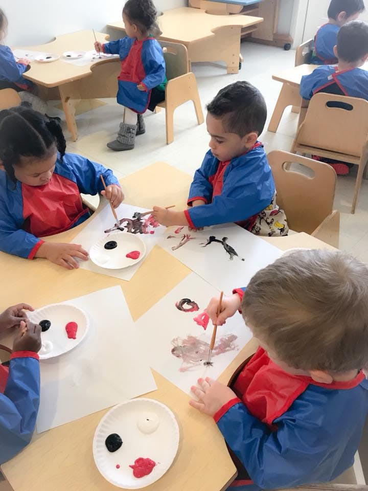 Children painting at tables in a classroom