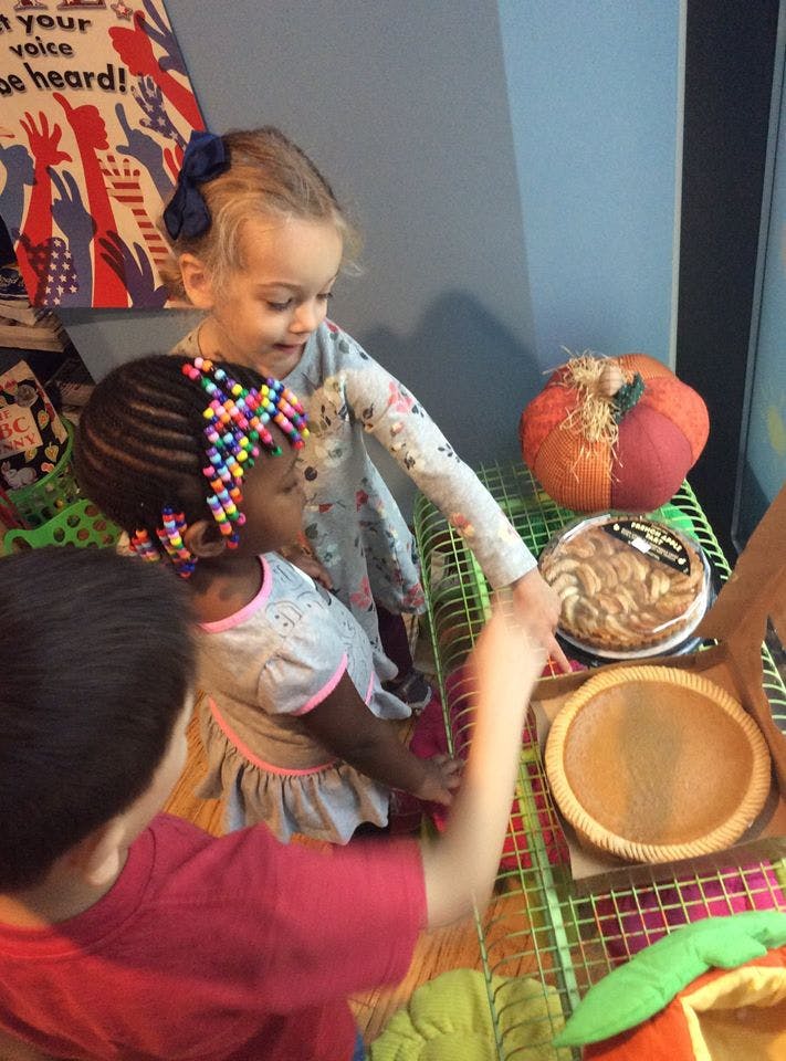 Two children looking at a pie and a pumpkin decoration