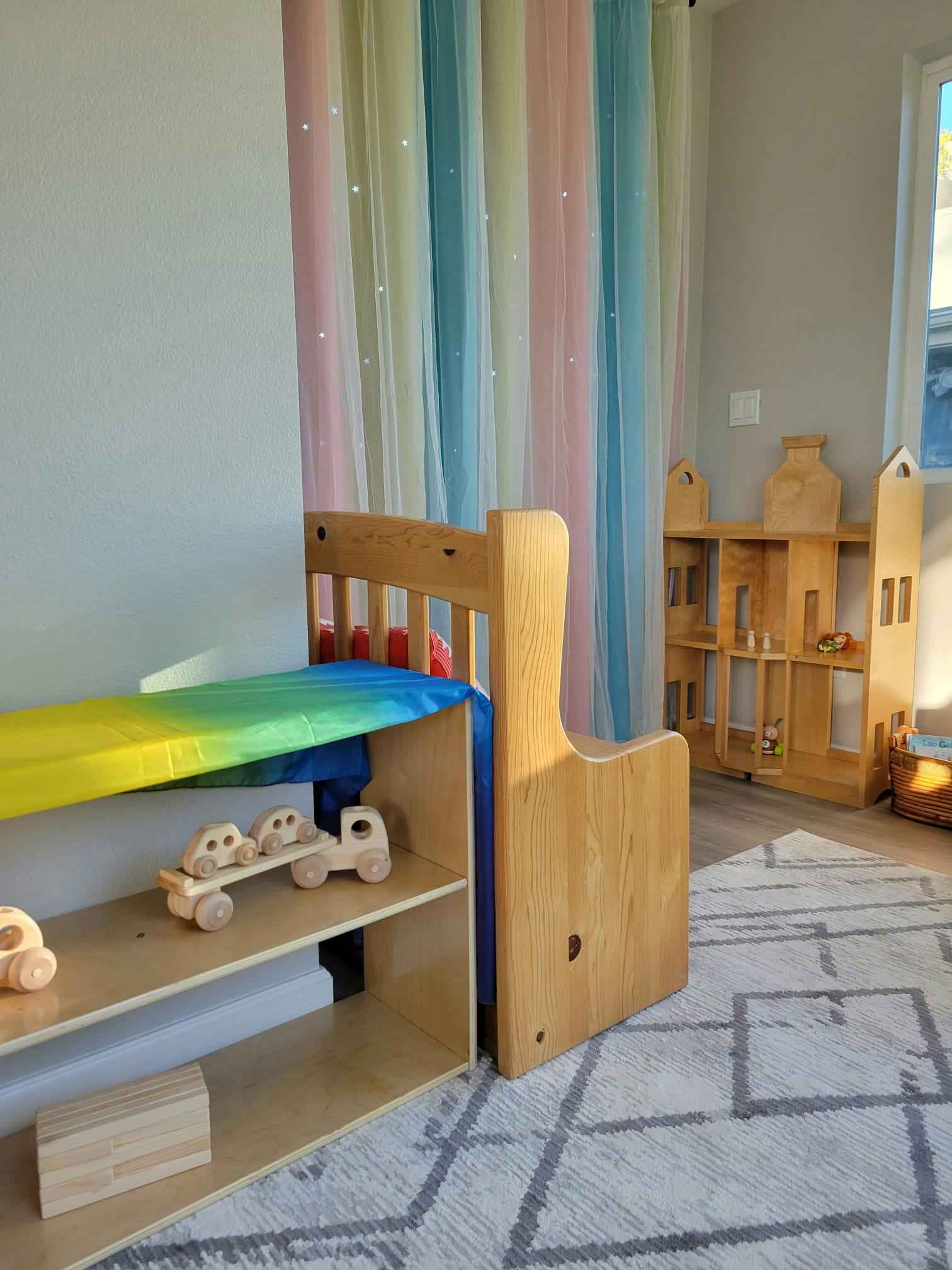 Wooden toy shelf with wooden cars and a dollhouse in a room with colorful curtains