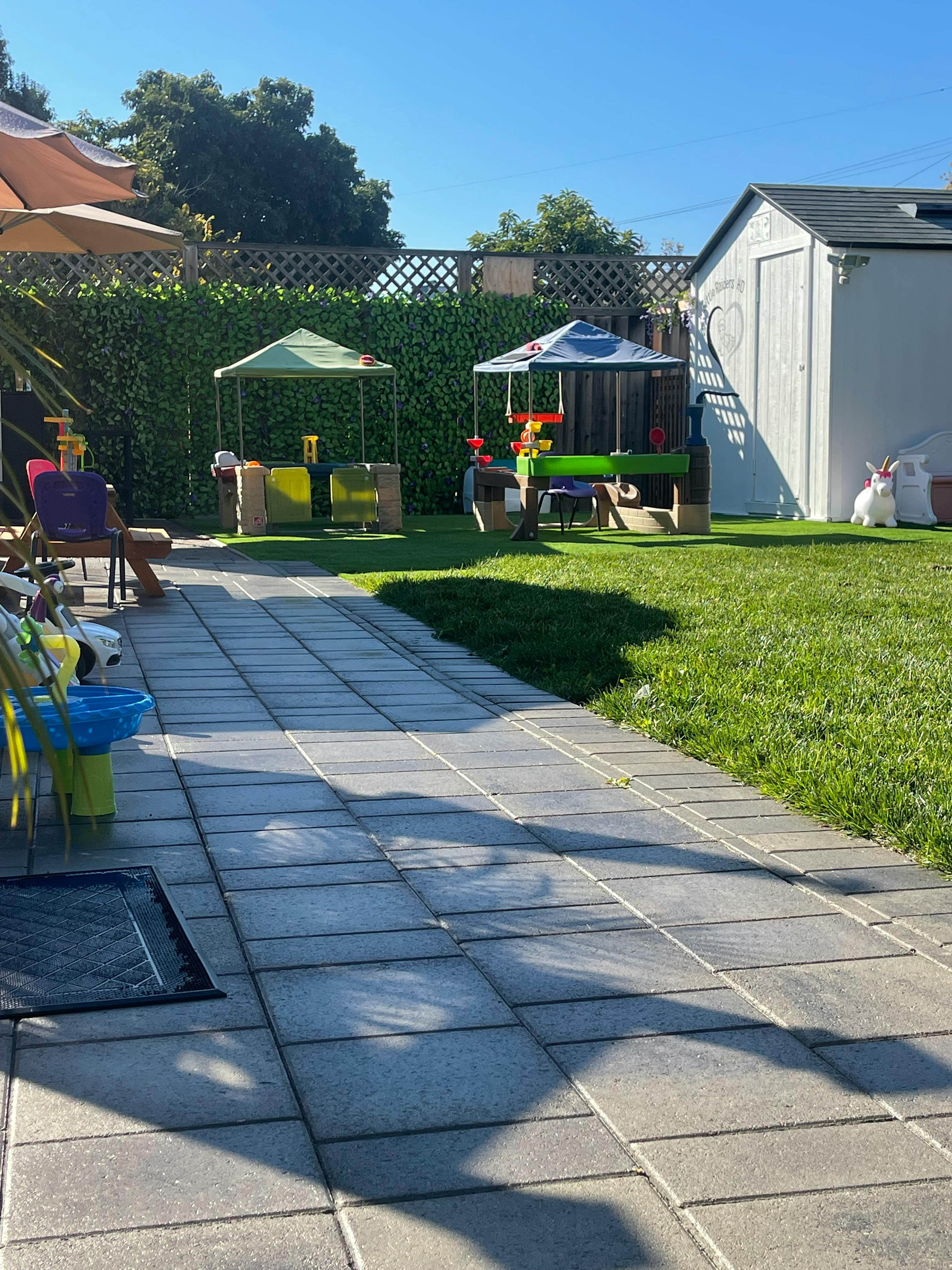 Backyard with a paved patio, green lawn, and two small play tents