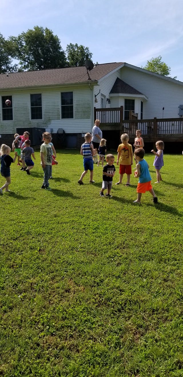 Children playing in a grassy yard with a house in the background
