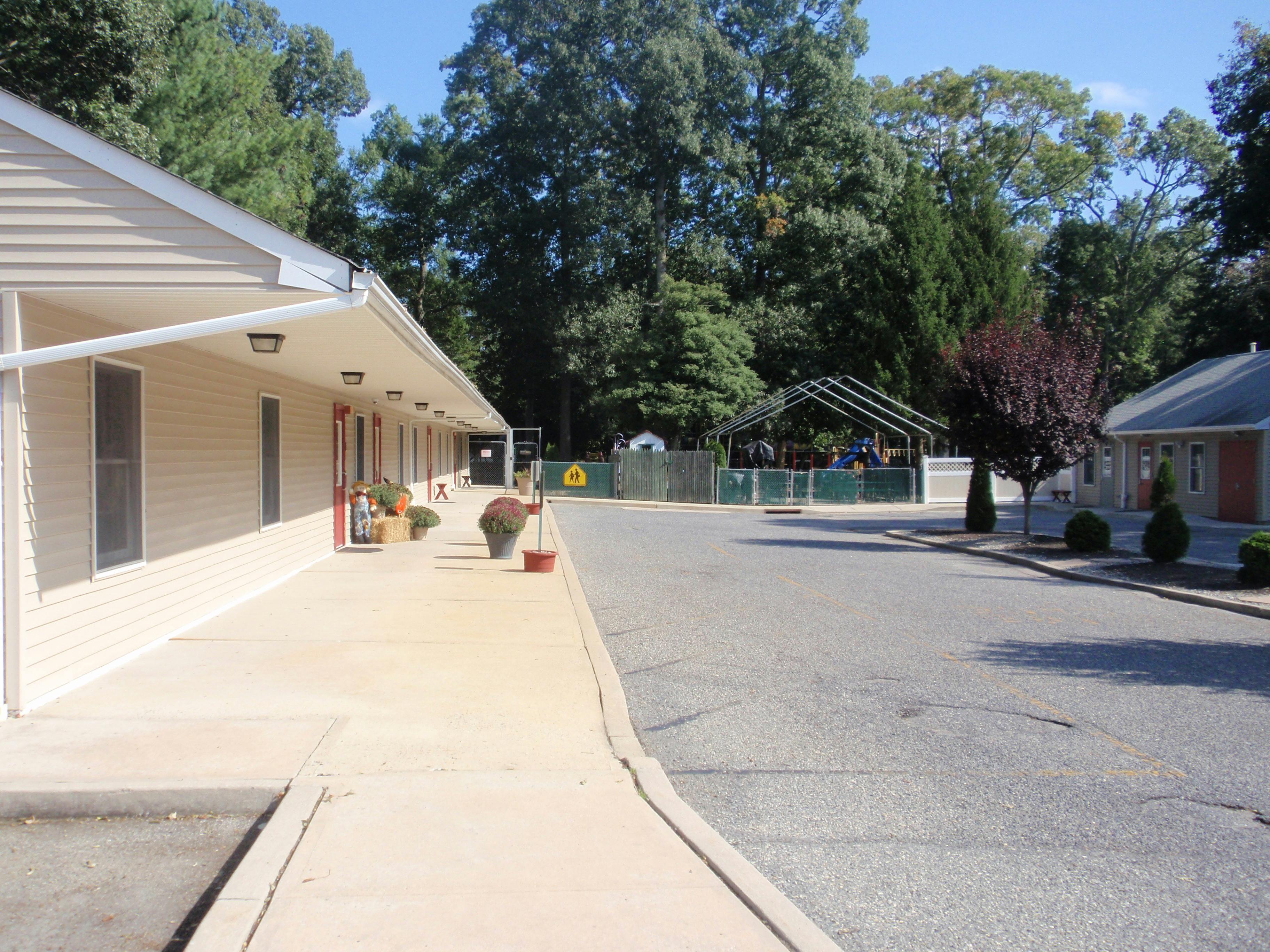 Building exterior with sidewalk and paved area leading to a tent structure