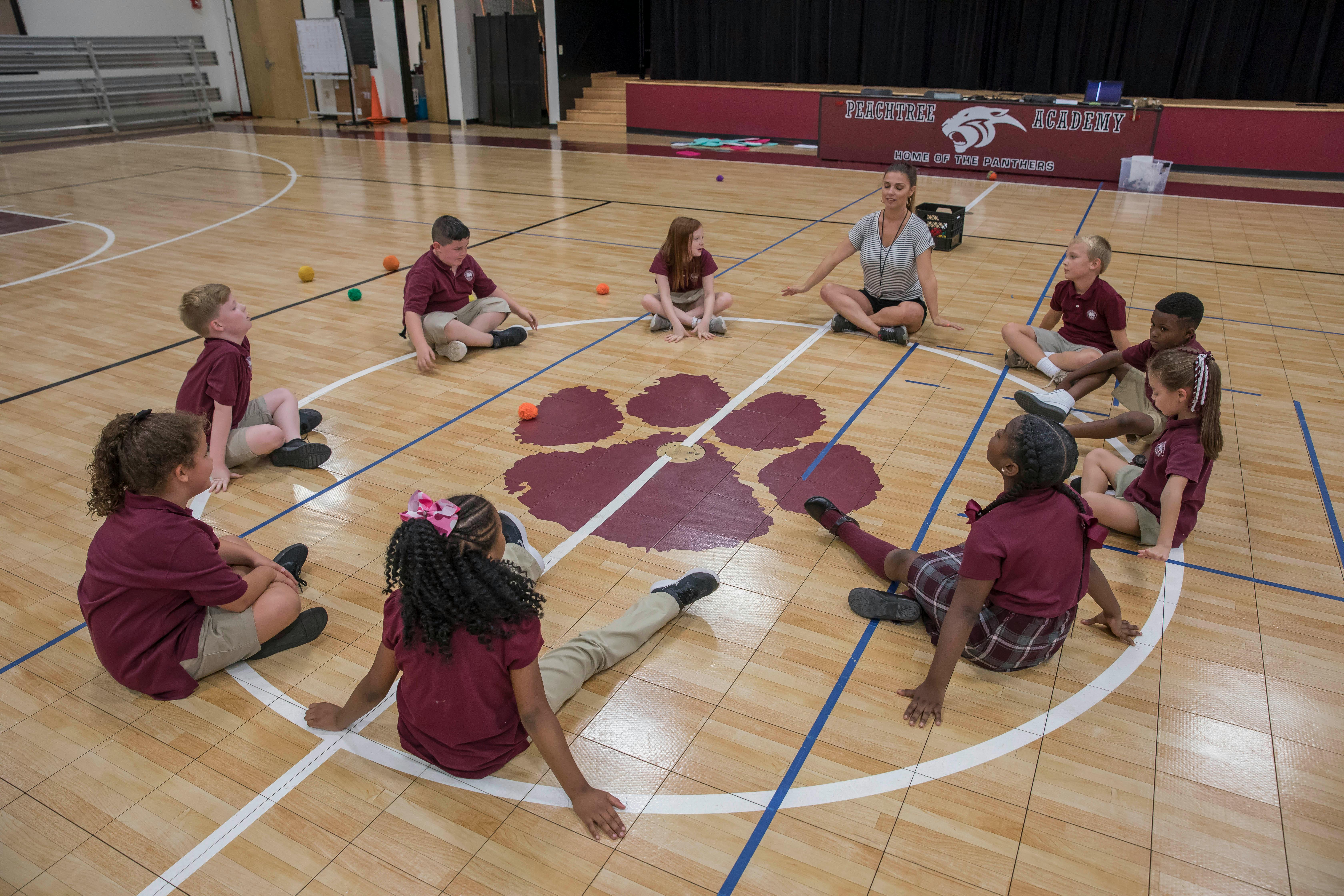 Adult and children sitting in a circle on a gym floor