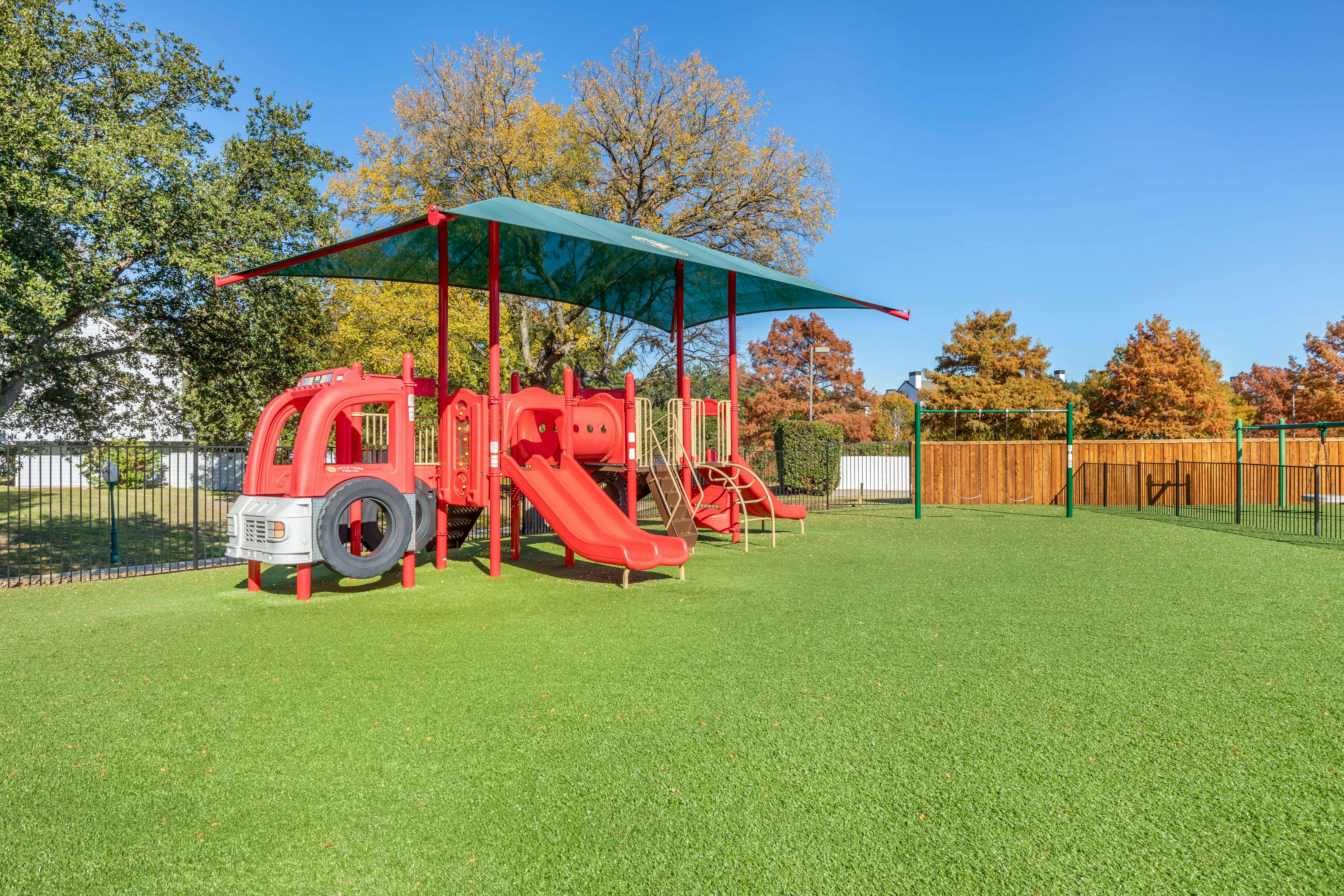 Red playground with slides and a climbing structure under a green canopy