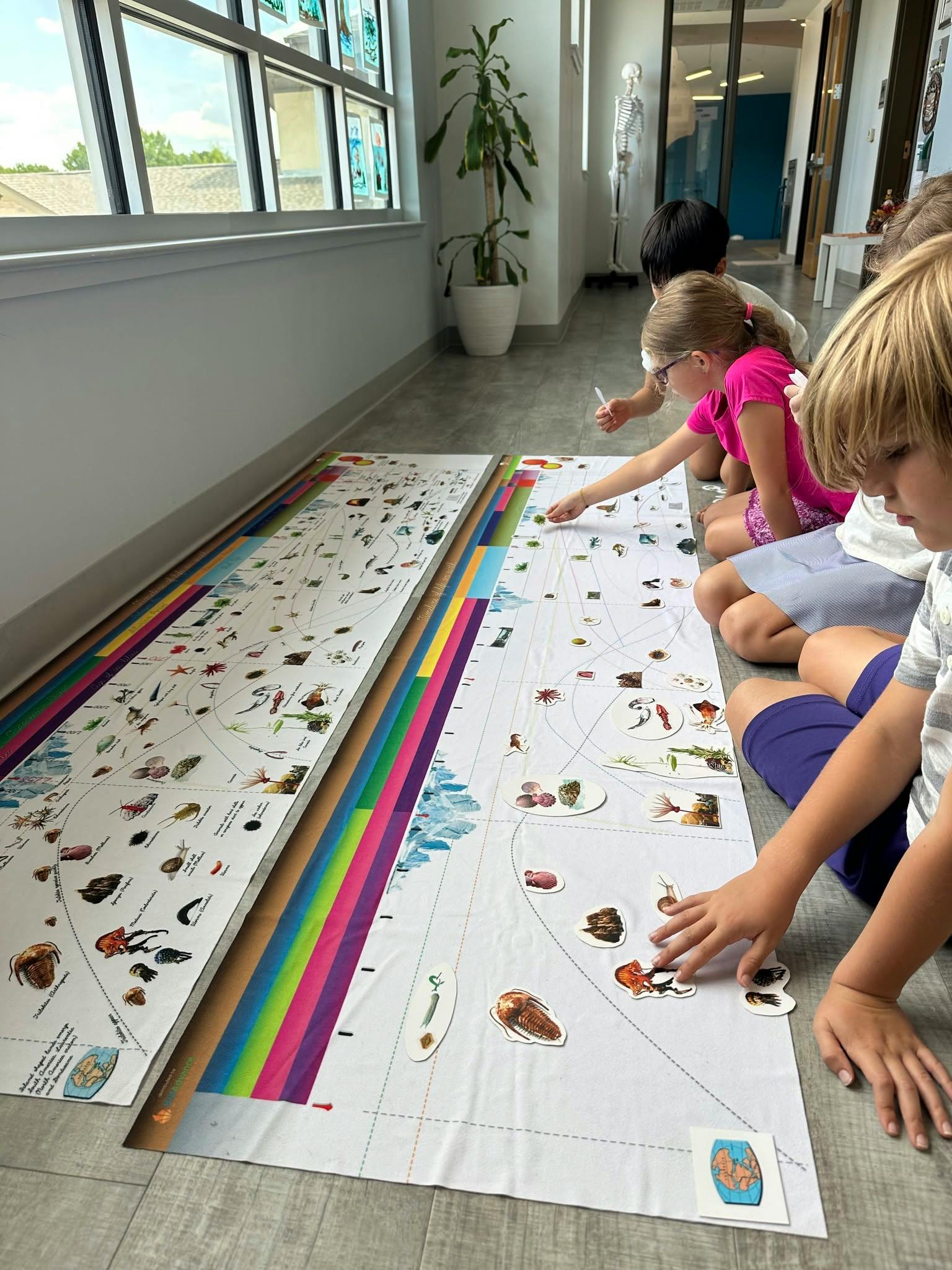 Children on the floor placing cutouts on a large timeline chart