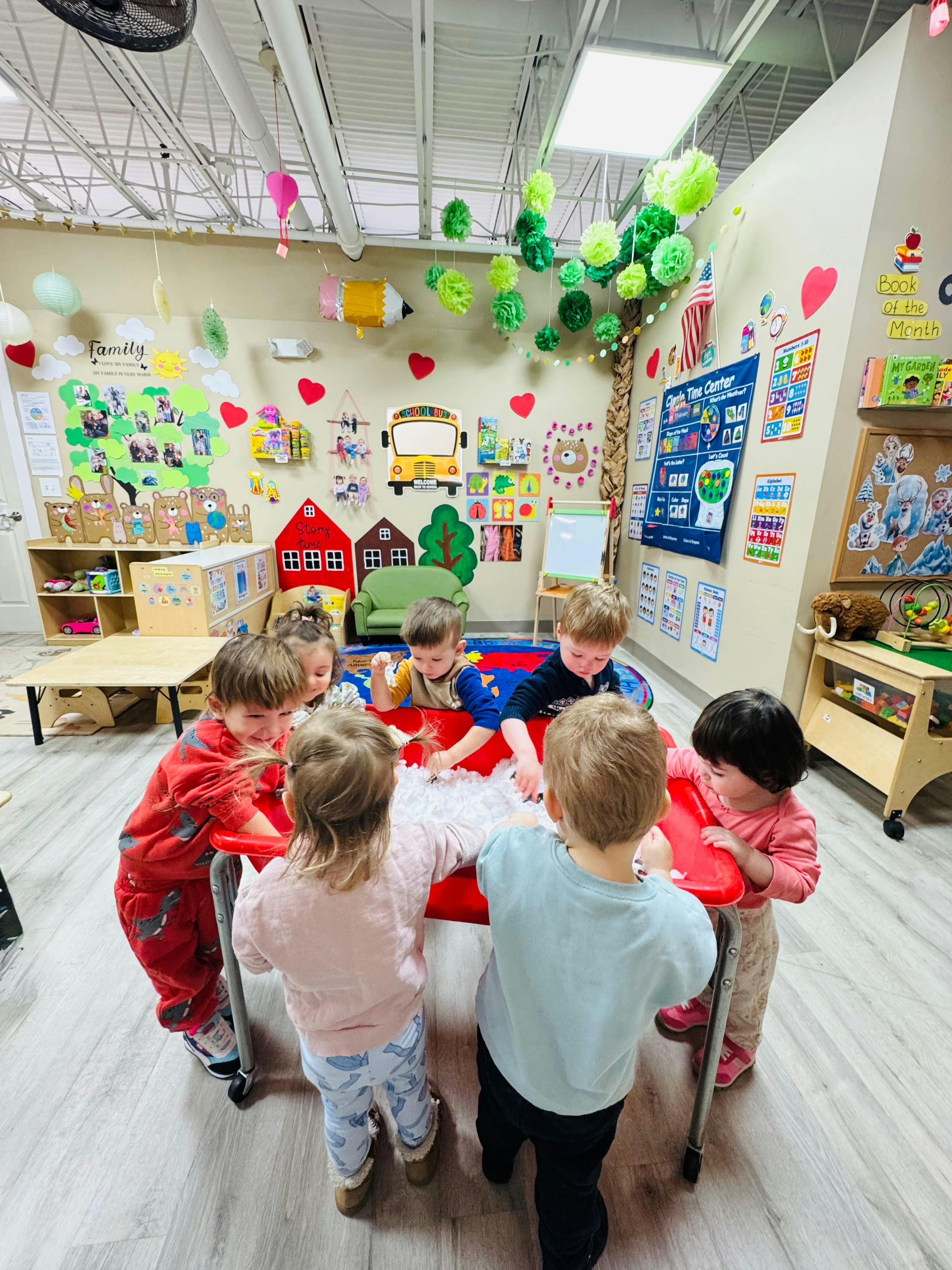 Group of children playing with materials at a sensory table in a classroom
