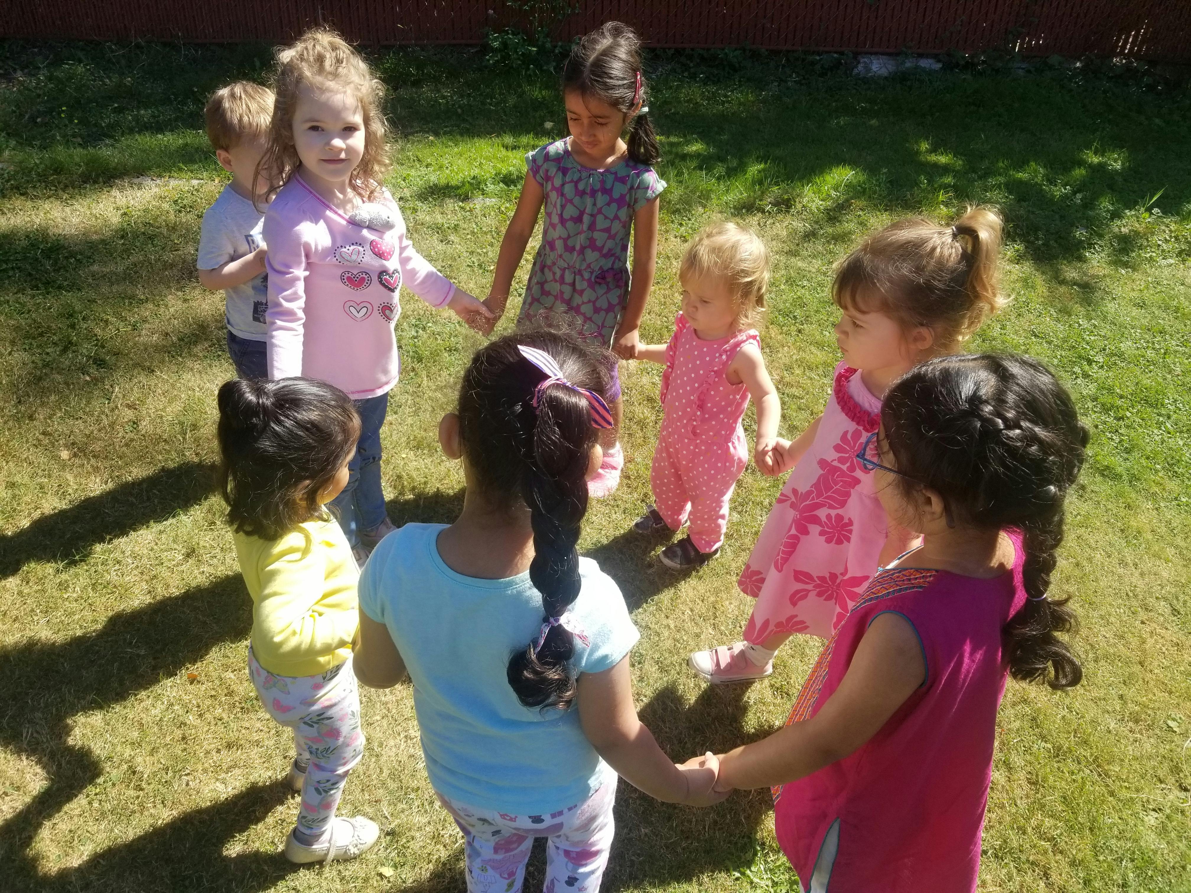 Group of children holding hands in a circle outdoors