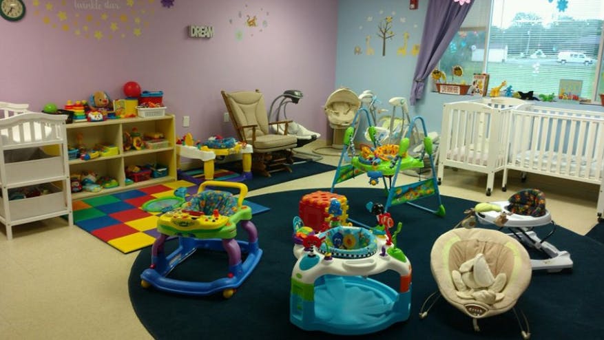 Infant room with cribs, play mats, and baby activity centers