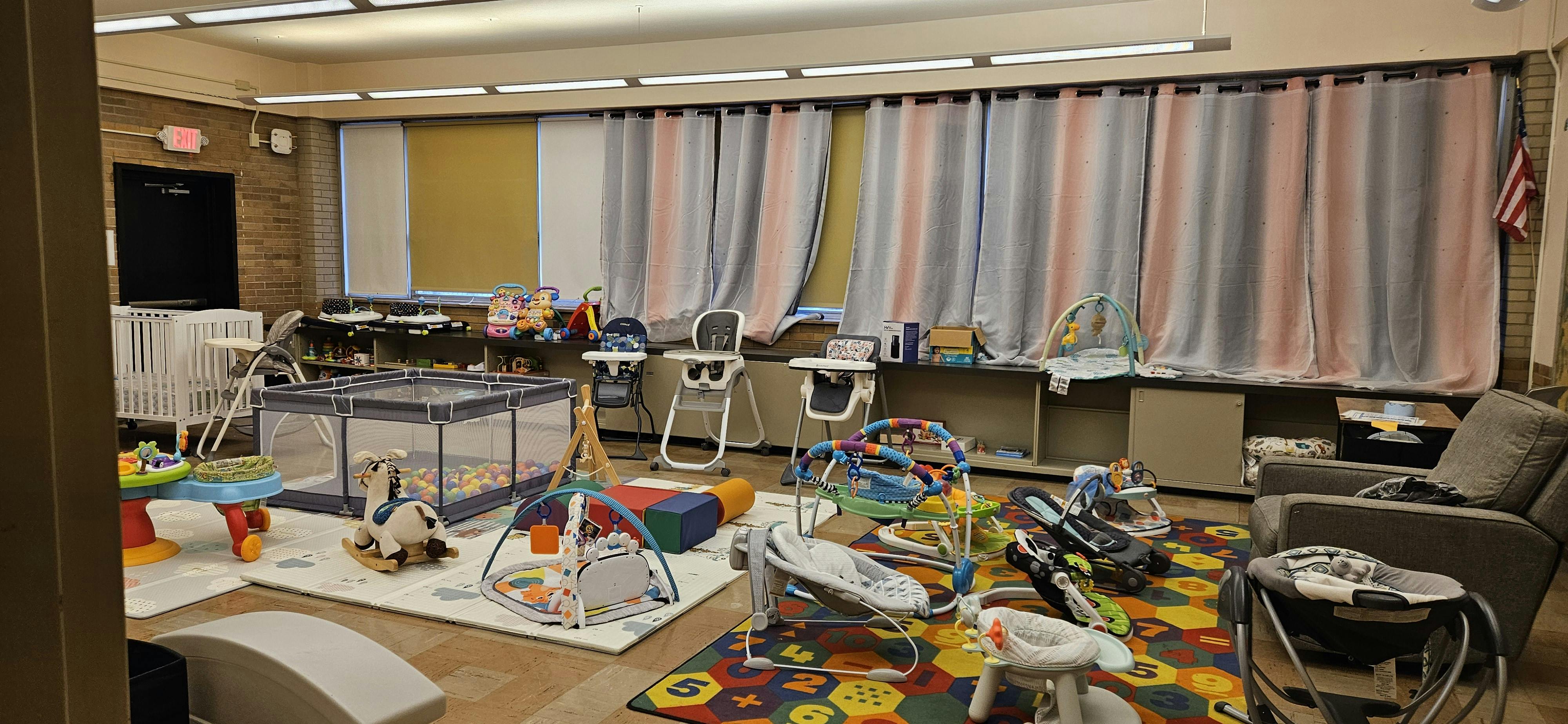 Room with baby playpens, high chairs, and infant activity centers