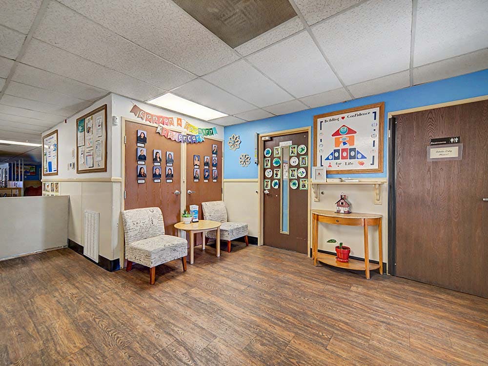 Lounge area in a daycare with chairs, table, and doors adorned with children's photos
