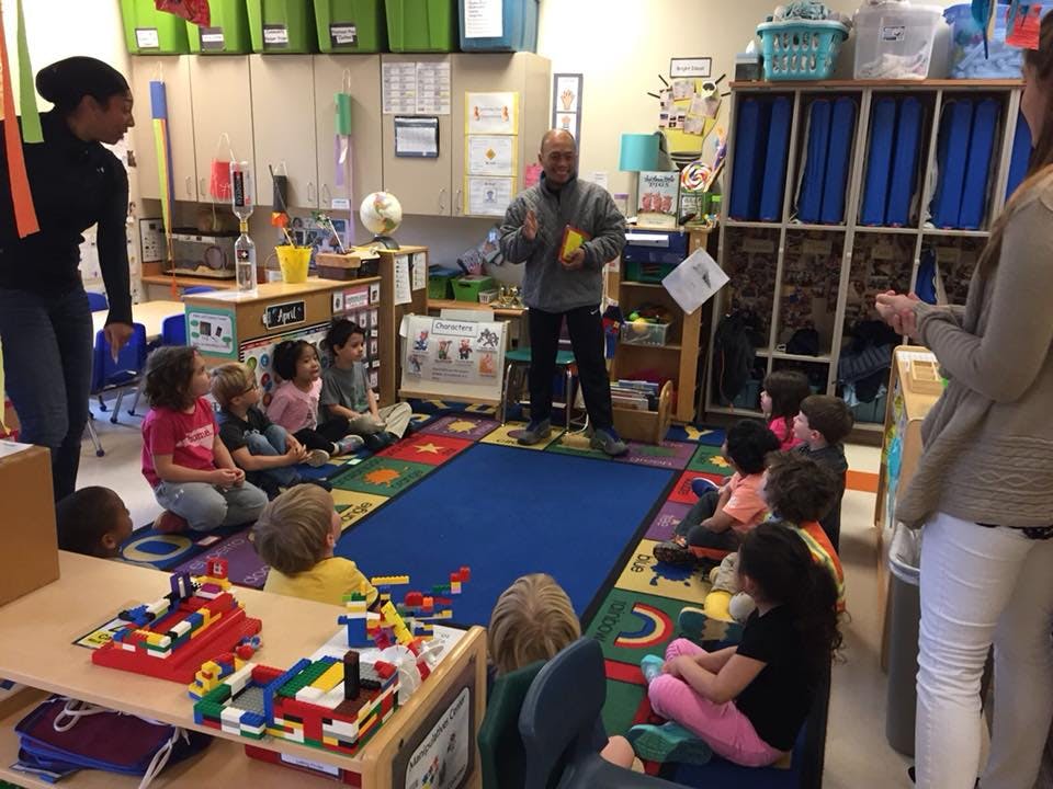 Adults and children sitting on a rug in a classroom