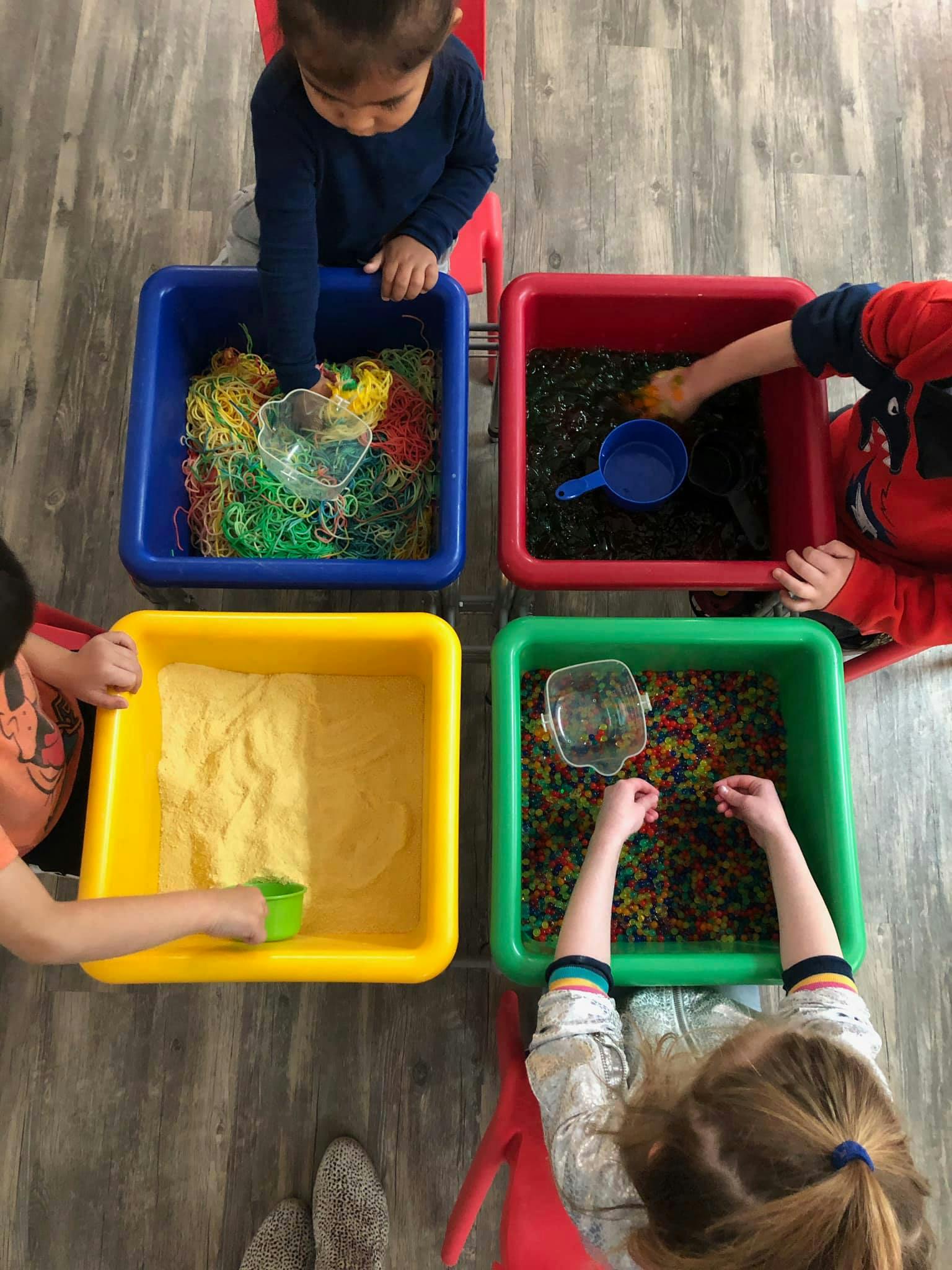 Children playing with sensory bins filled with various materials