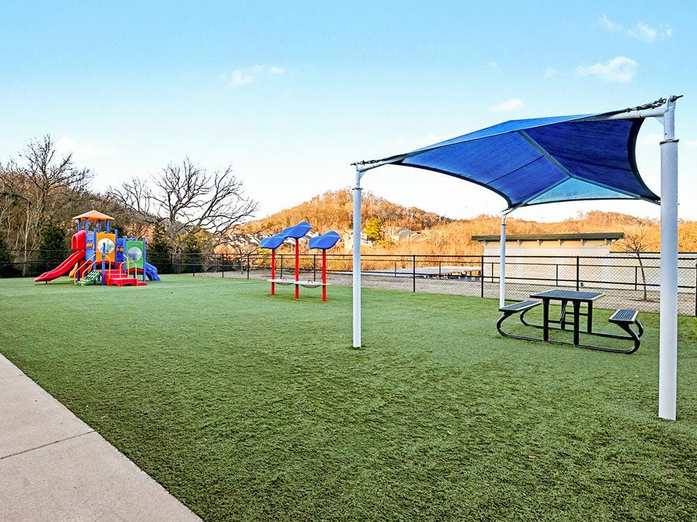 Playground with colorful play structures on artificial turf under a blue sky