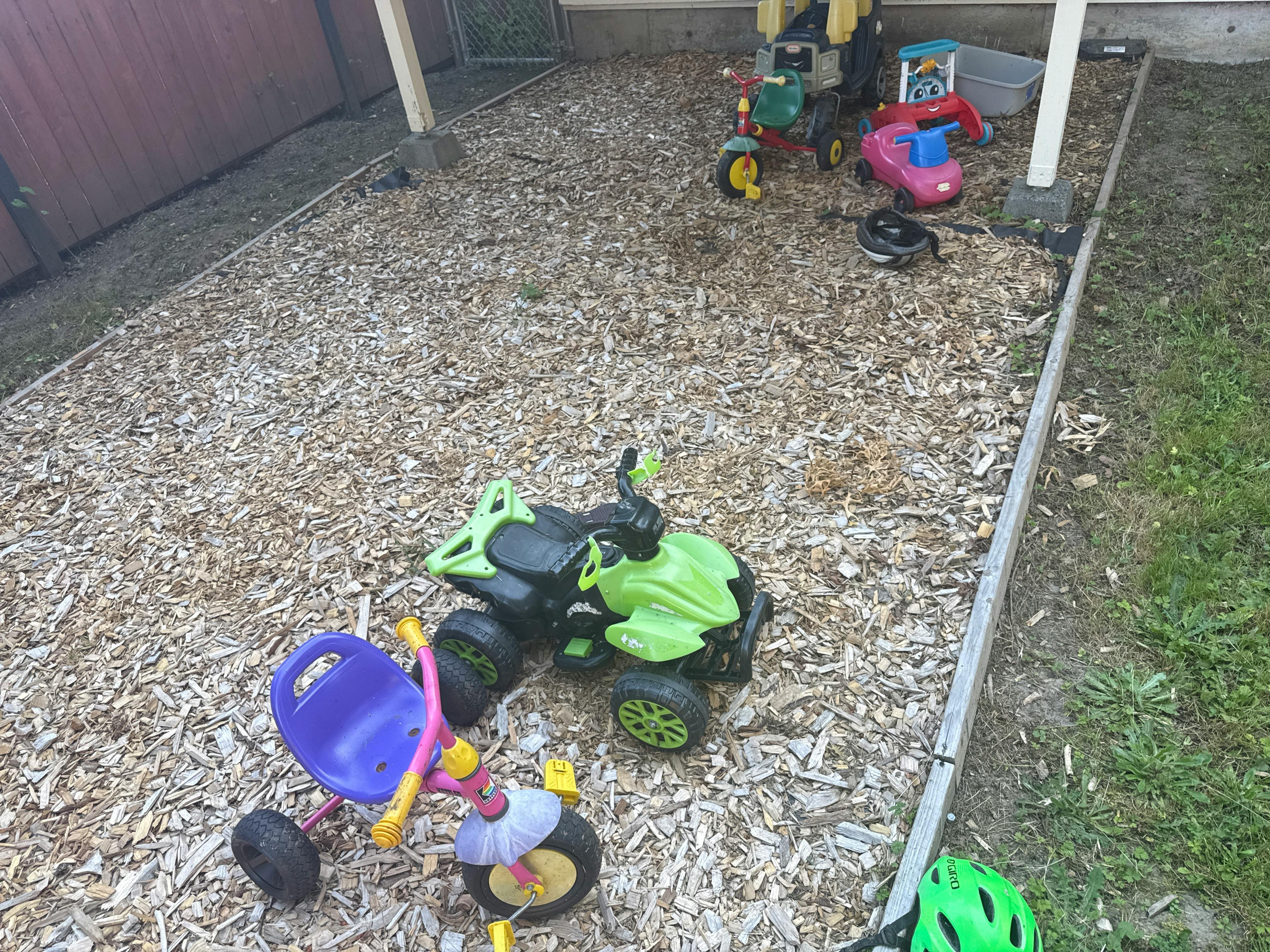 Collection of children's ride-on toys in a wood chip yard