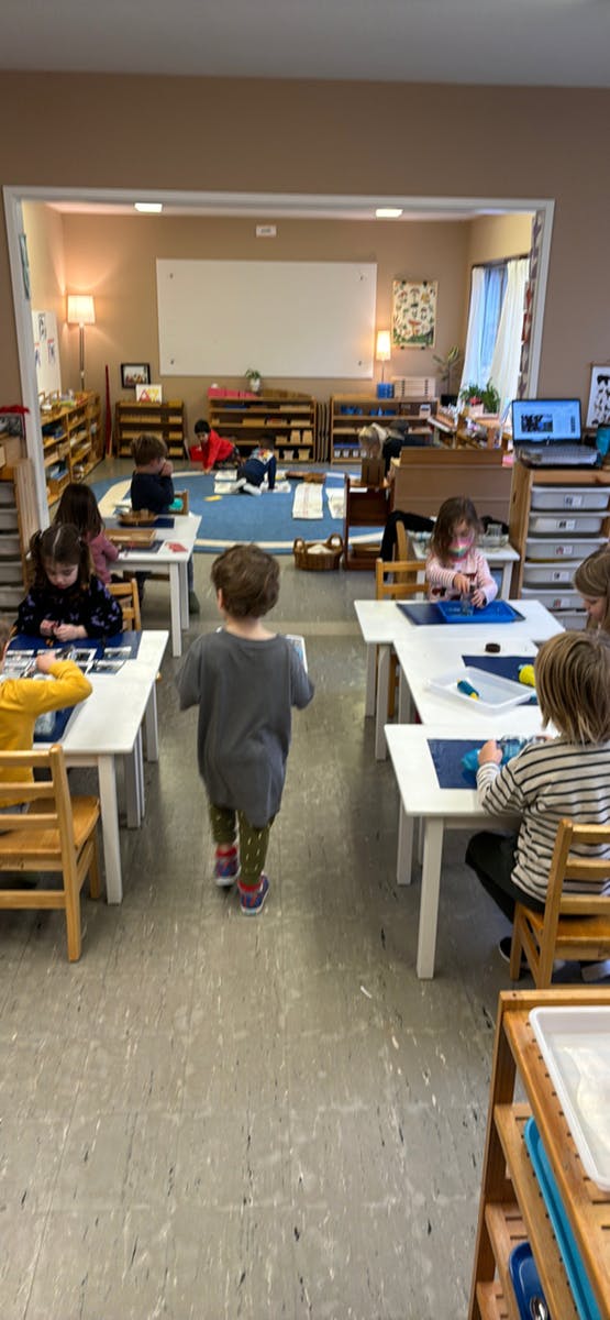 Children working at tables and on the floor in a classroom