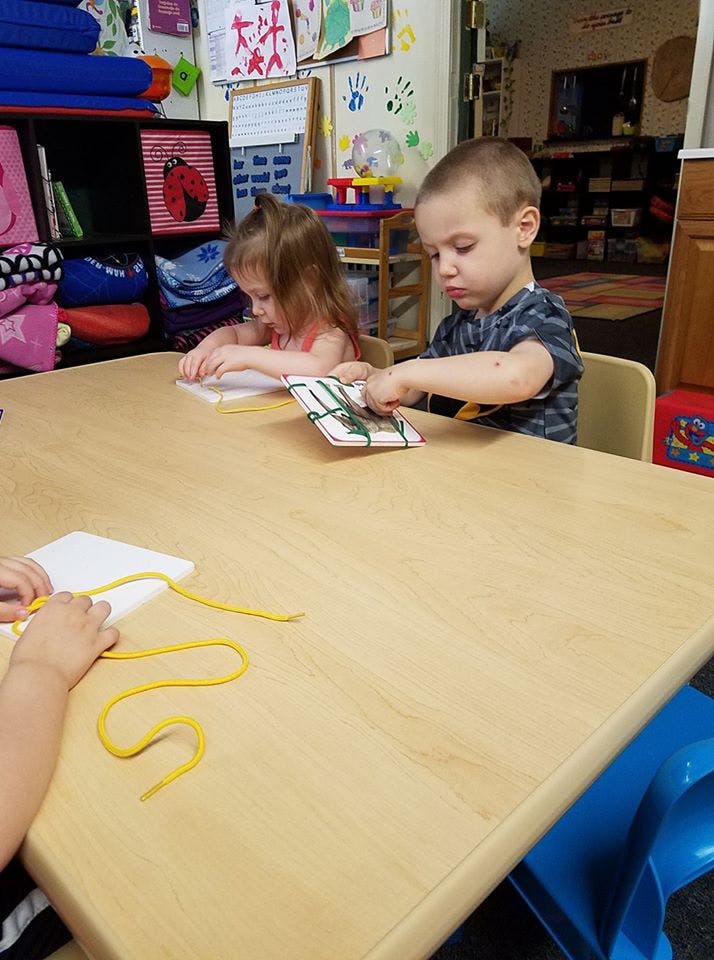 Children at a table working with lacing cards and stringing activities