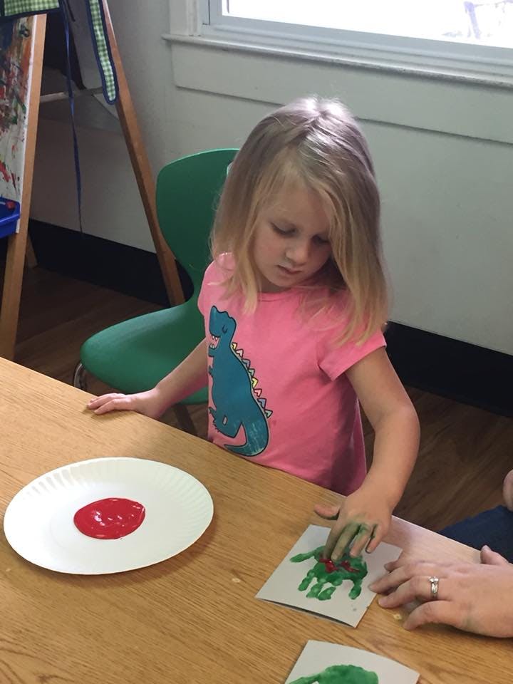 Child making a handprint with green paint