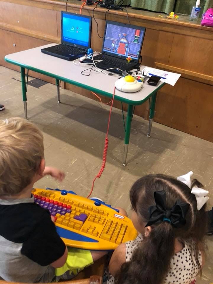 Two children playing with a large yellow keyboard toy