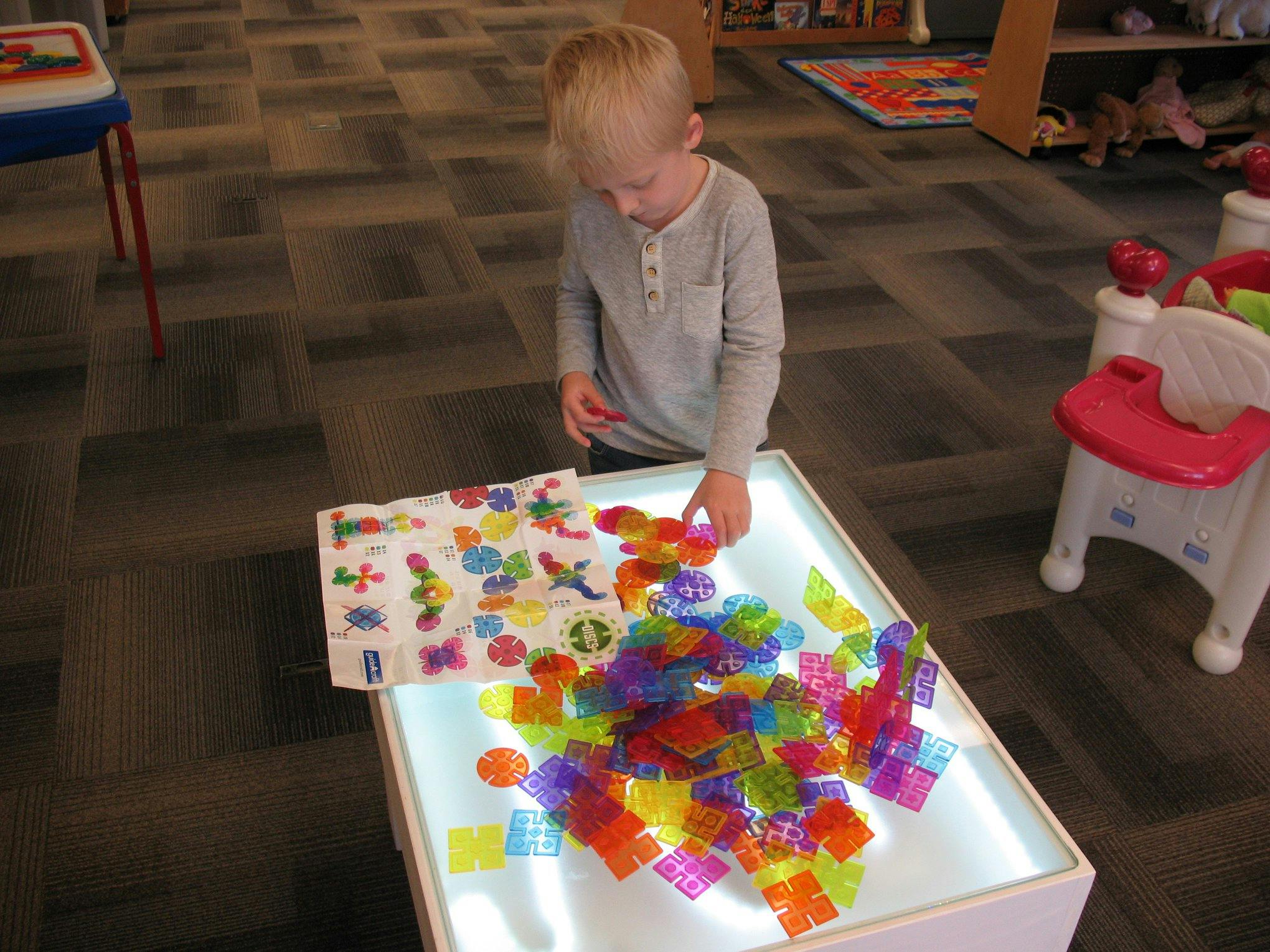 Child playing with colorful translucent blocks on a light table