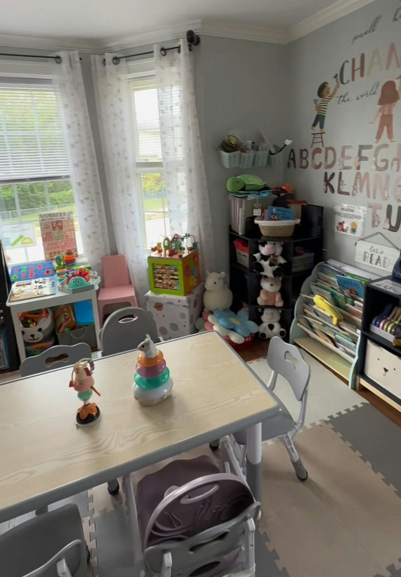 A children's play area with a table, chairs, toys, and alphabet wall decals