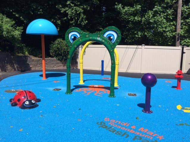 Splash pad with a frog arch, ladybug, and other water features