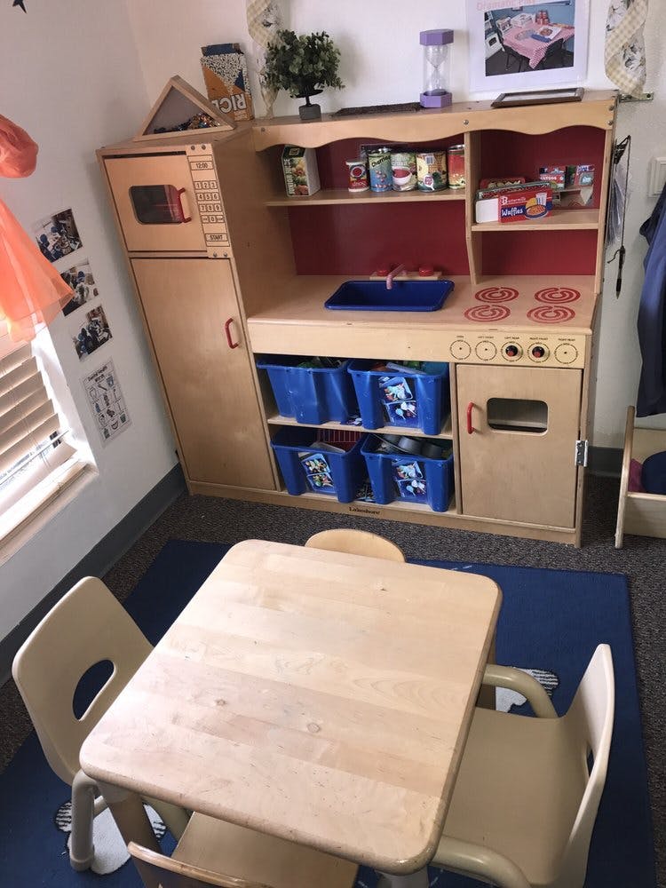 Play kitchen with blue bins and a small table with two chairs