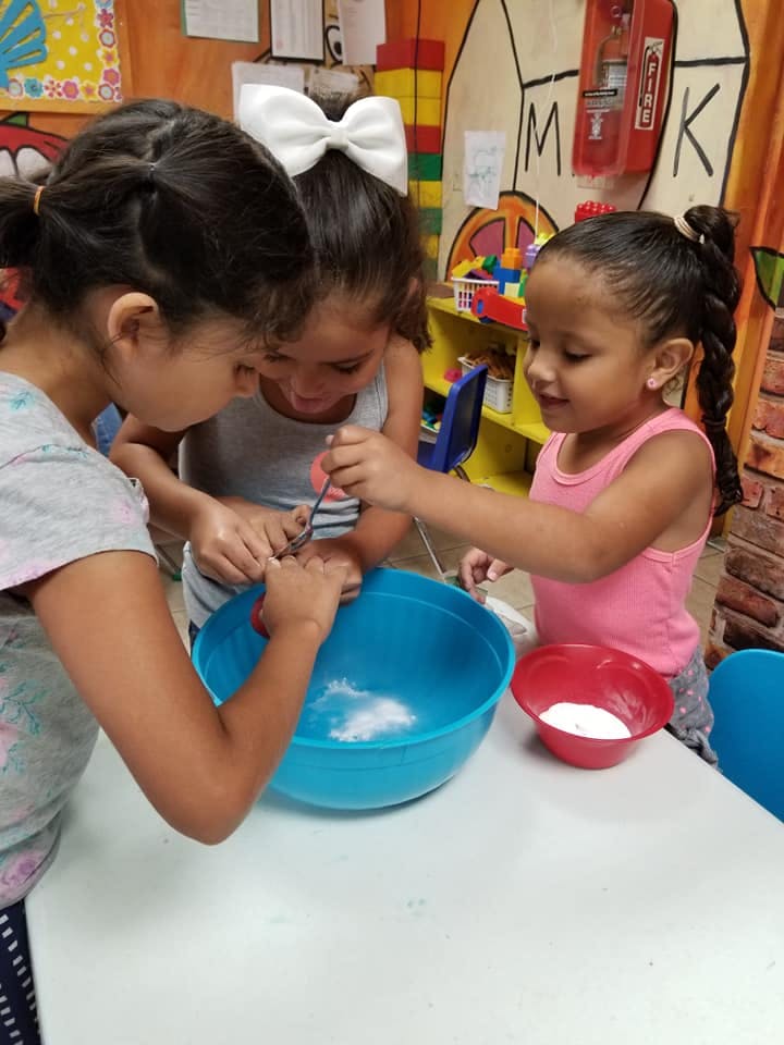 Three children mixing ingredients in bowls at a table