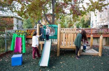 Adult and children playing on a playground slide and slide