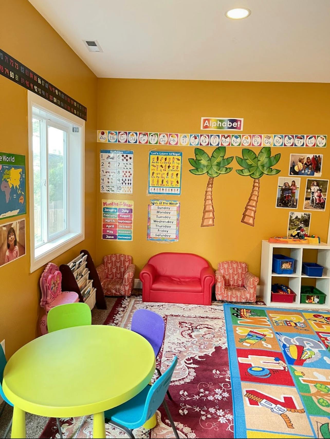 Classroom with small table and chairs, alphabet on wall, and play rug