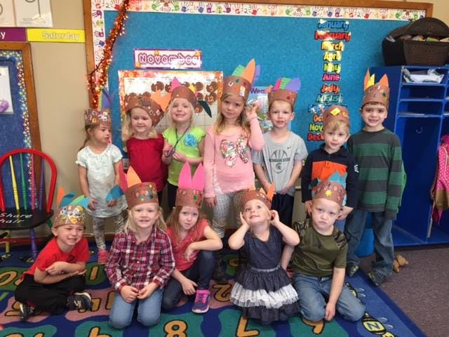 Group of children wearing paper crowns in a classroom