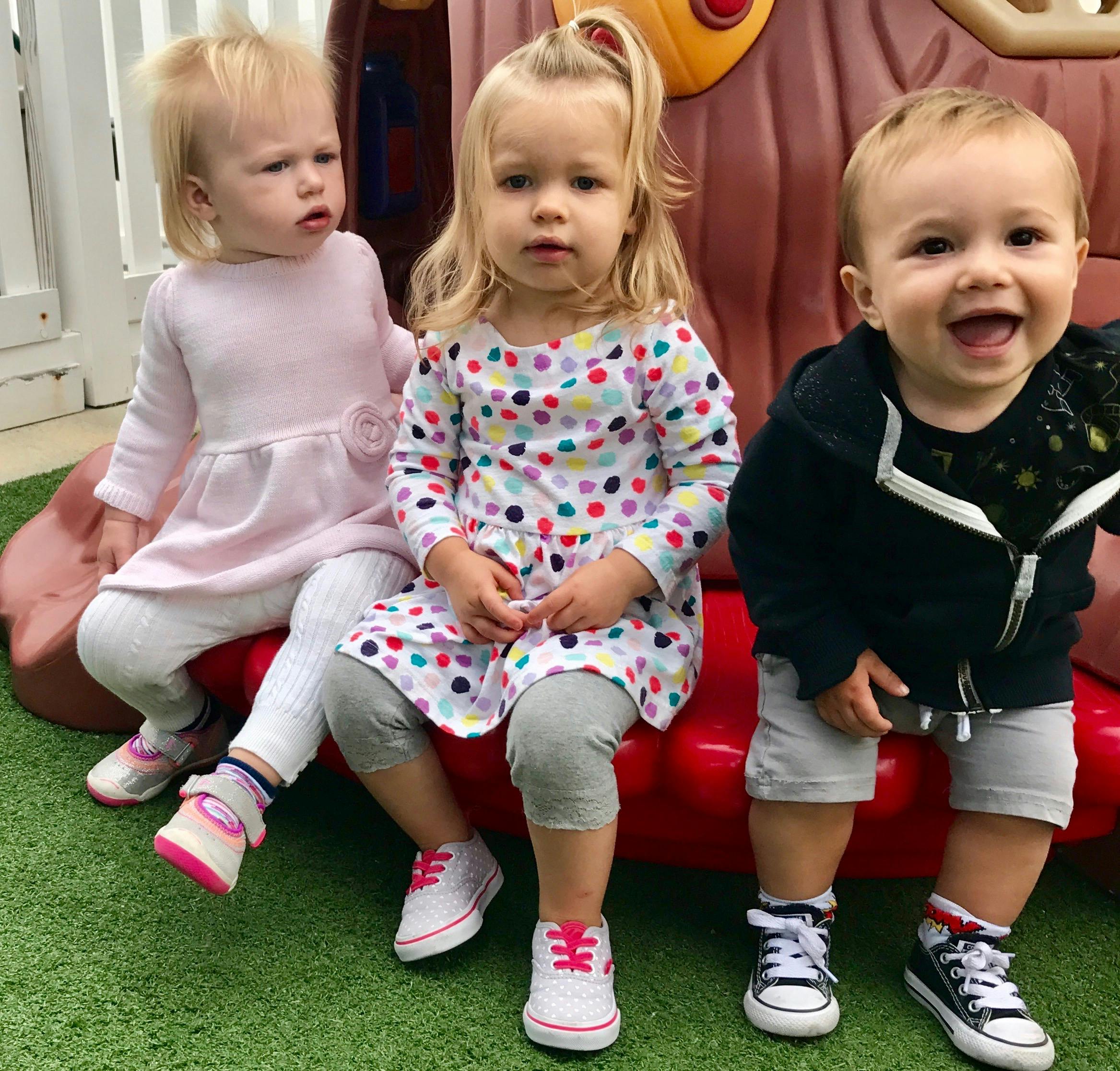 Three children sitting on a red play structure