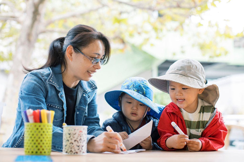 Person and two children drawing at a table