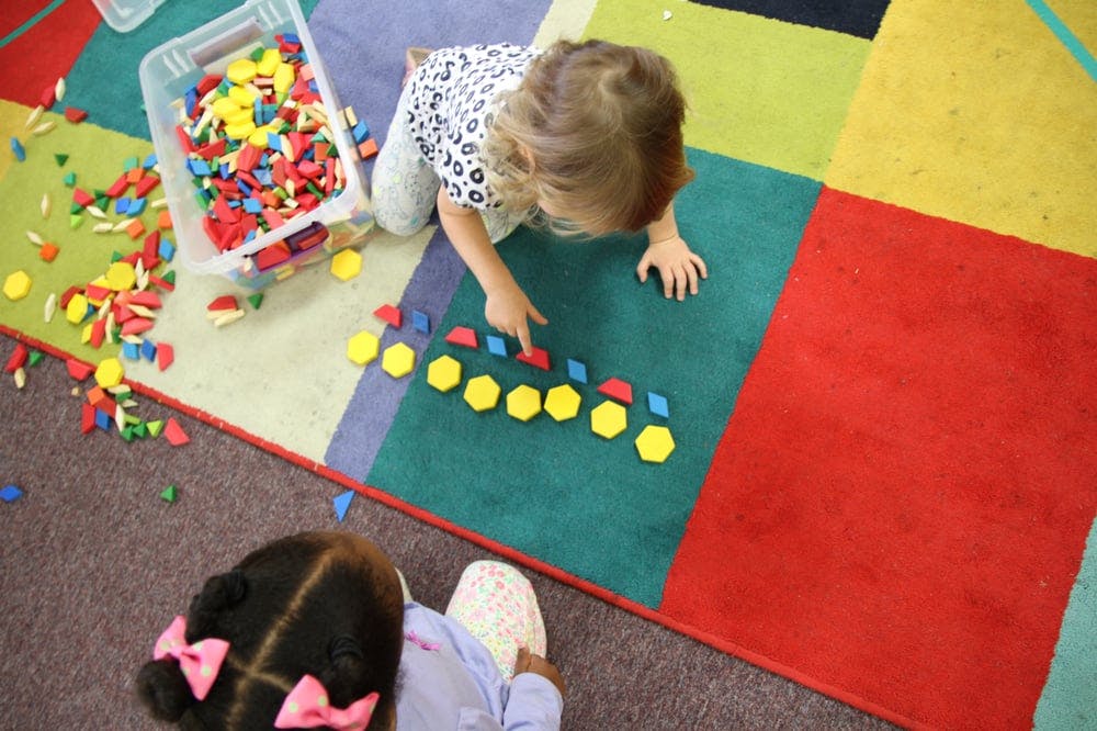 Child playing with colorful geometric shapes on a rug