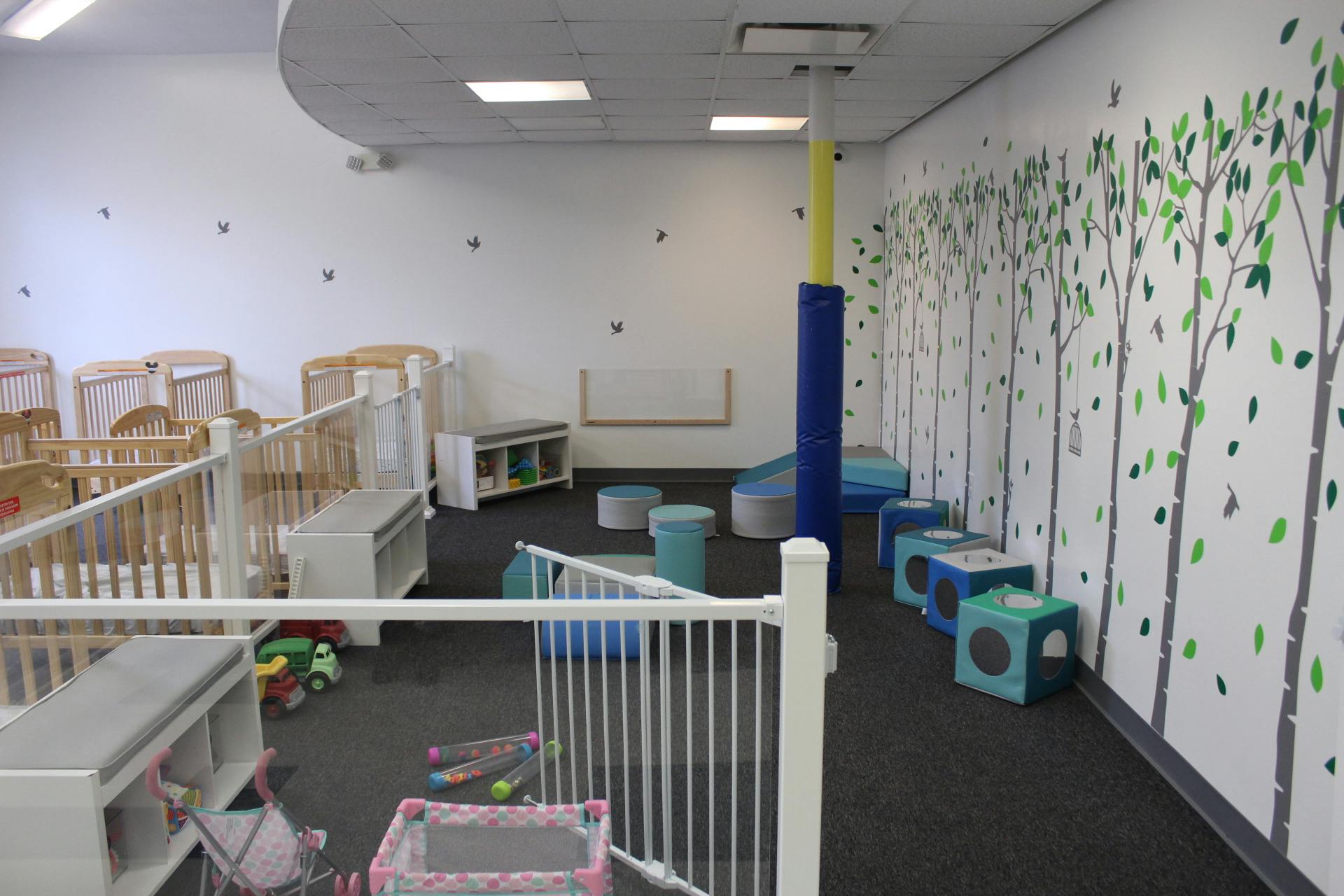 Empty daycare room with cribs and play area