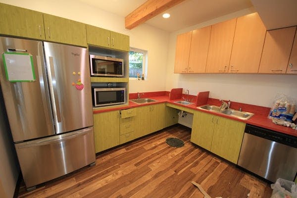 Kitchen with stainless steel refrigerator, two microwaves, and red countertops
