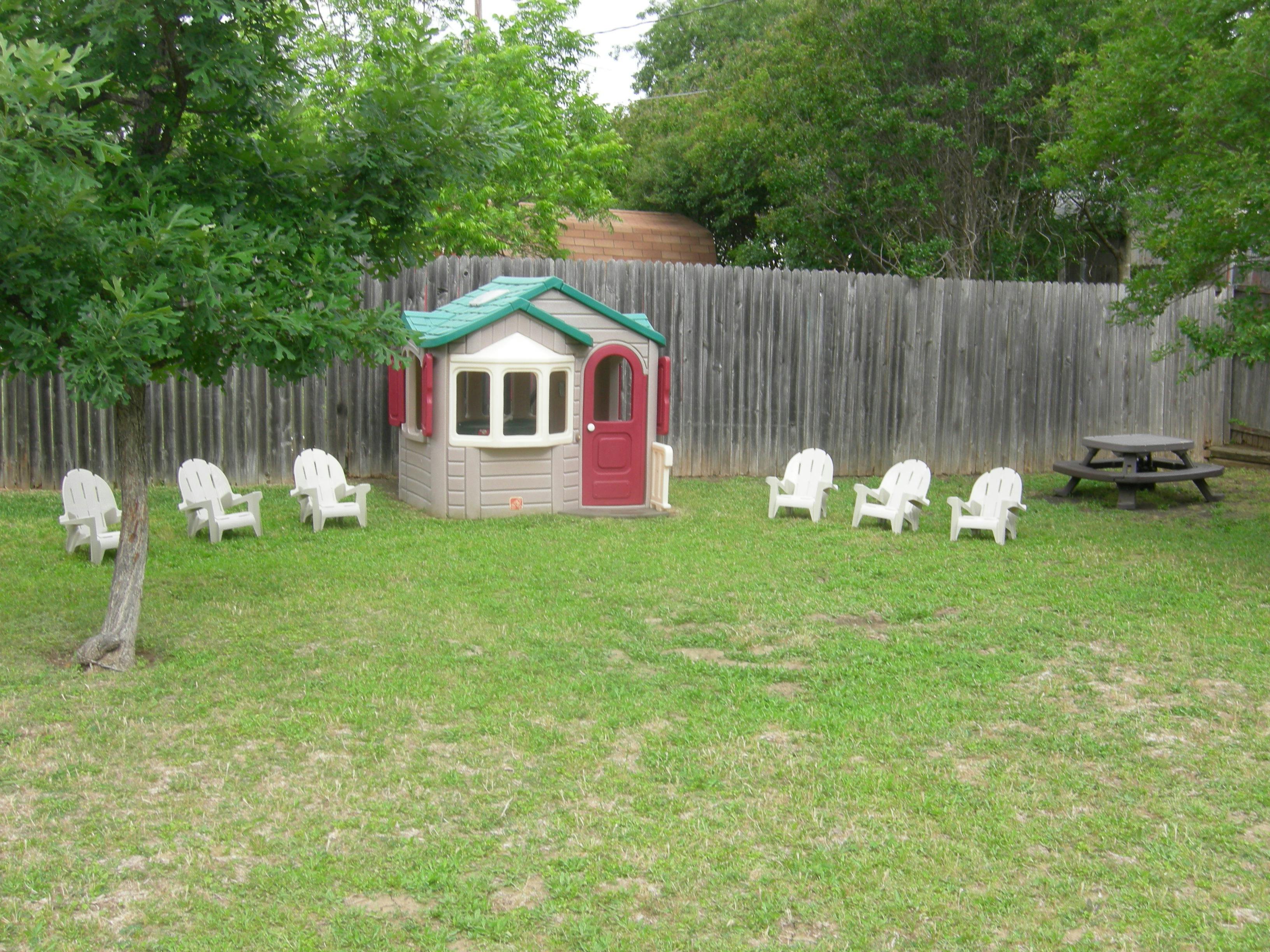 Playhouse and chairs in a grassy yard